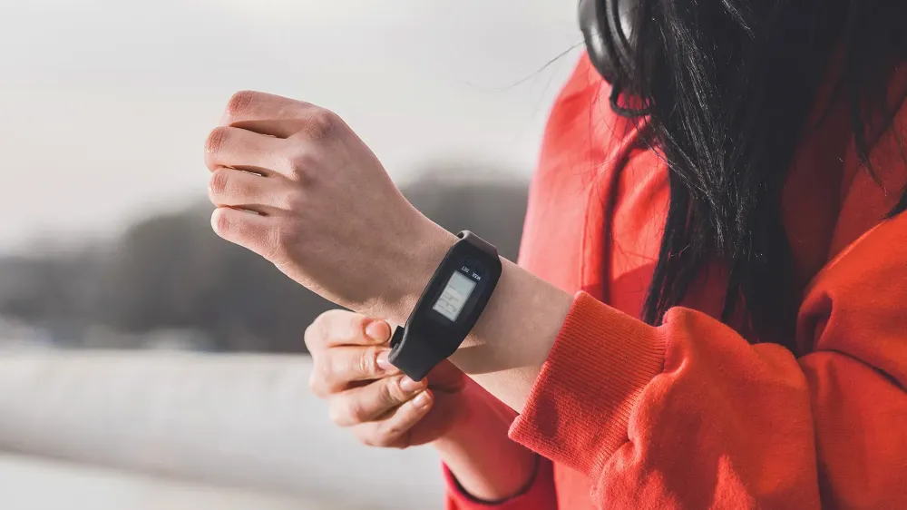 Closeup cropped photo of female runner putting a pedometer on her wrist